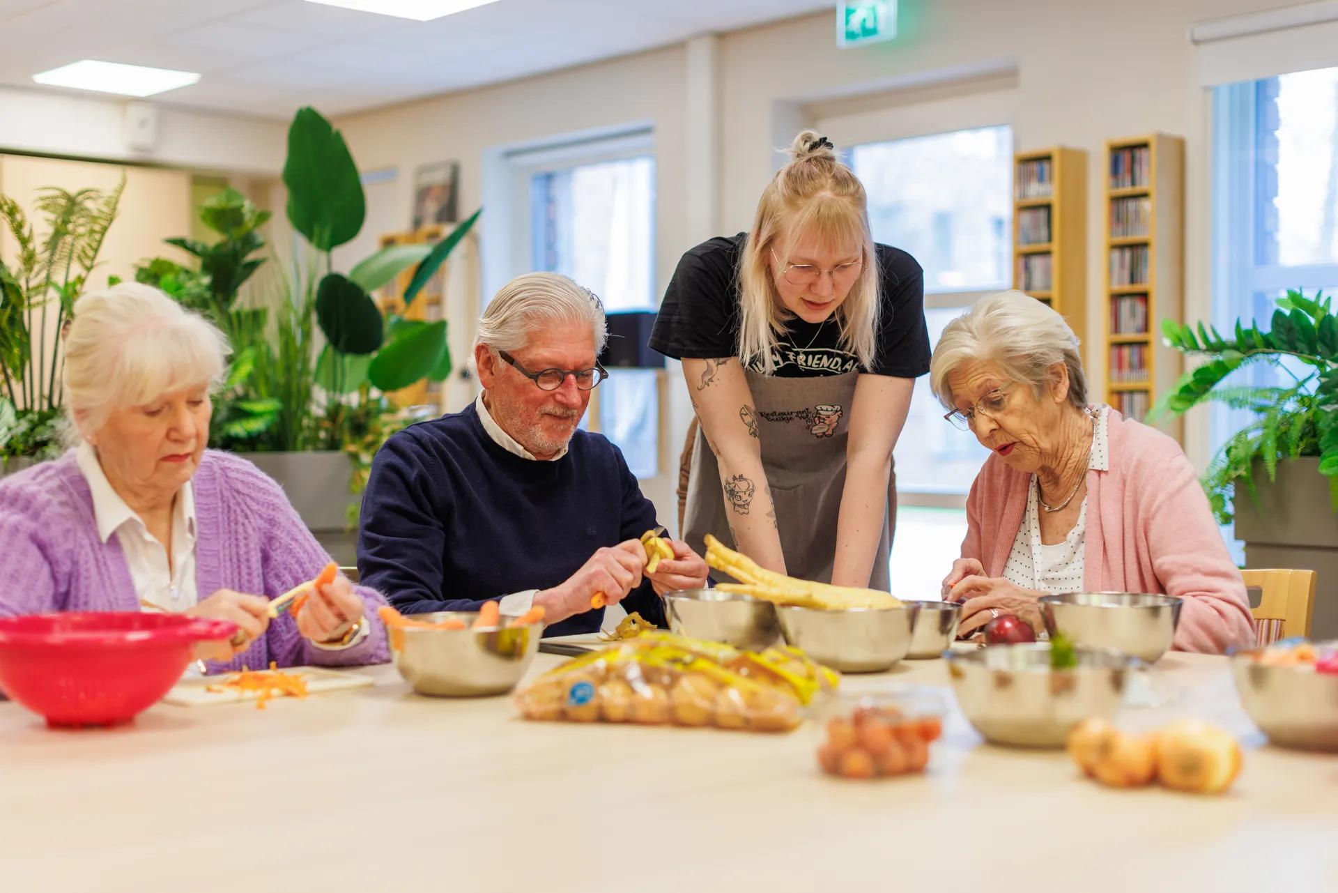 drie ouderen en een medewerker zijn aan het koken