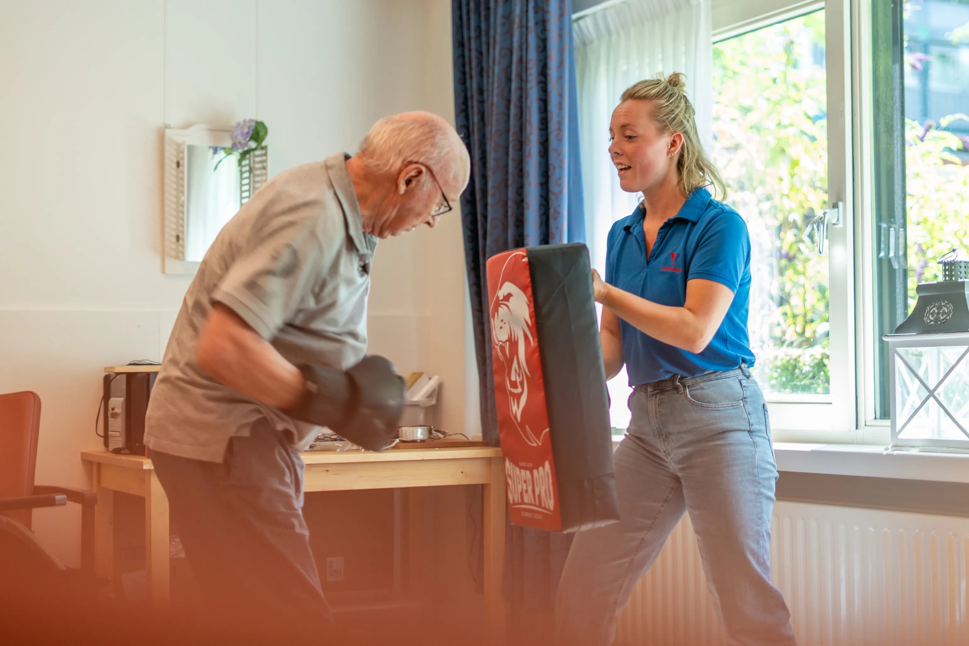 Een meneer doet boksoefeningen onder begeleiding van een fysiotherapeut.