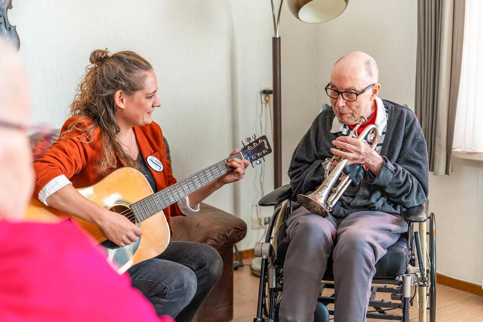 Oudere op trompet en behandelaar met gitaar