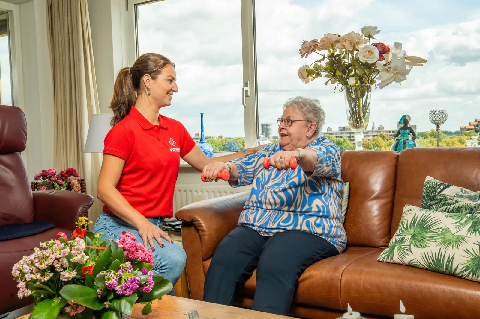 Fysiotherapeut laat mevrouw oefenen met kleine halters